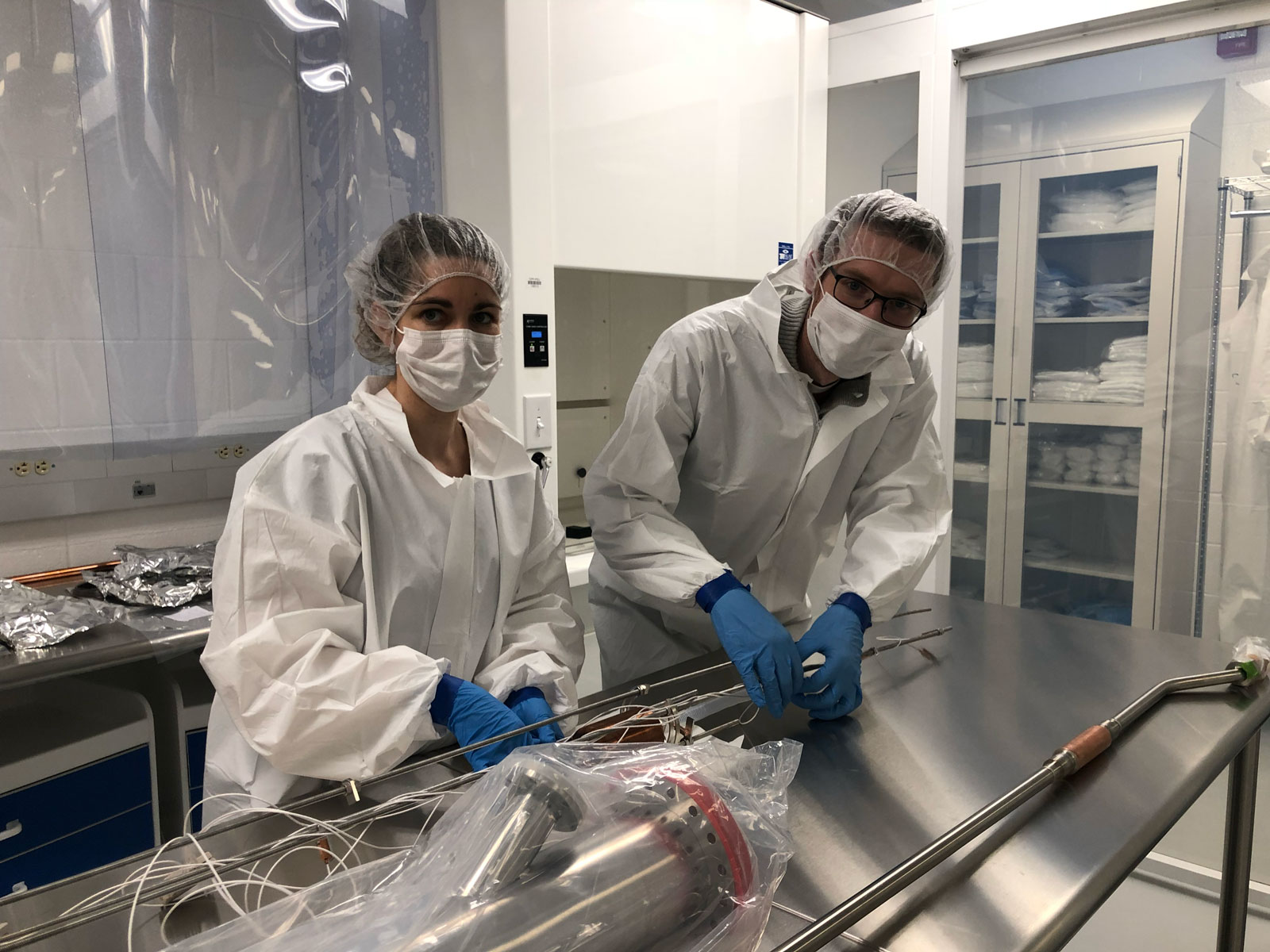 Carmona-Benitez and Woodward wear clean suits and work over metal table