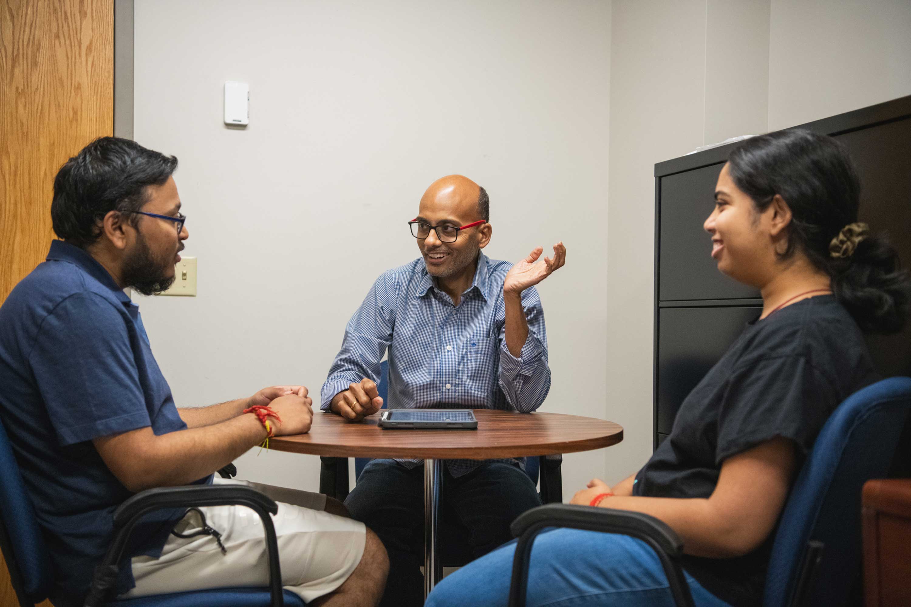 Bharath Sriperumbudur sits at table with two students