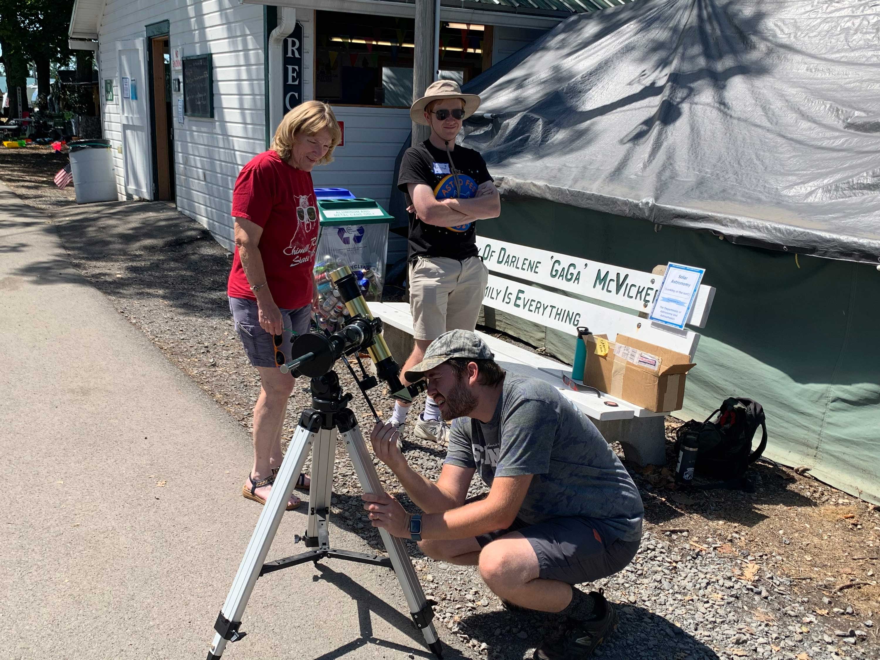 man looks through telescope at grange fair