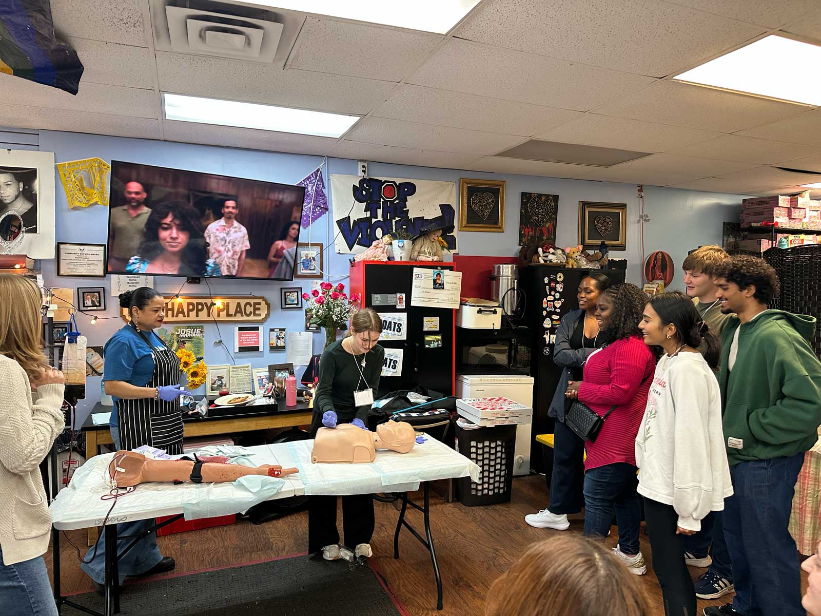 student looks at CPR dummy on table while other students look on