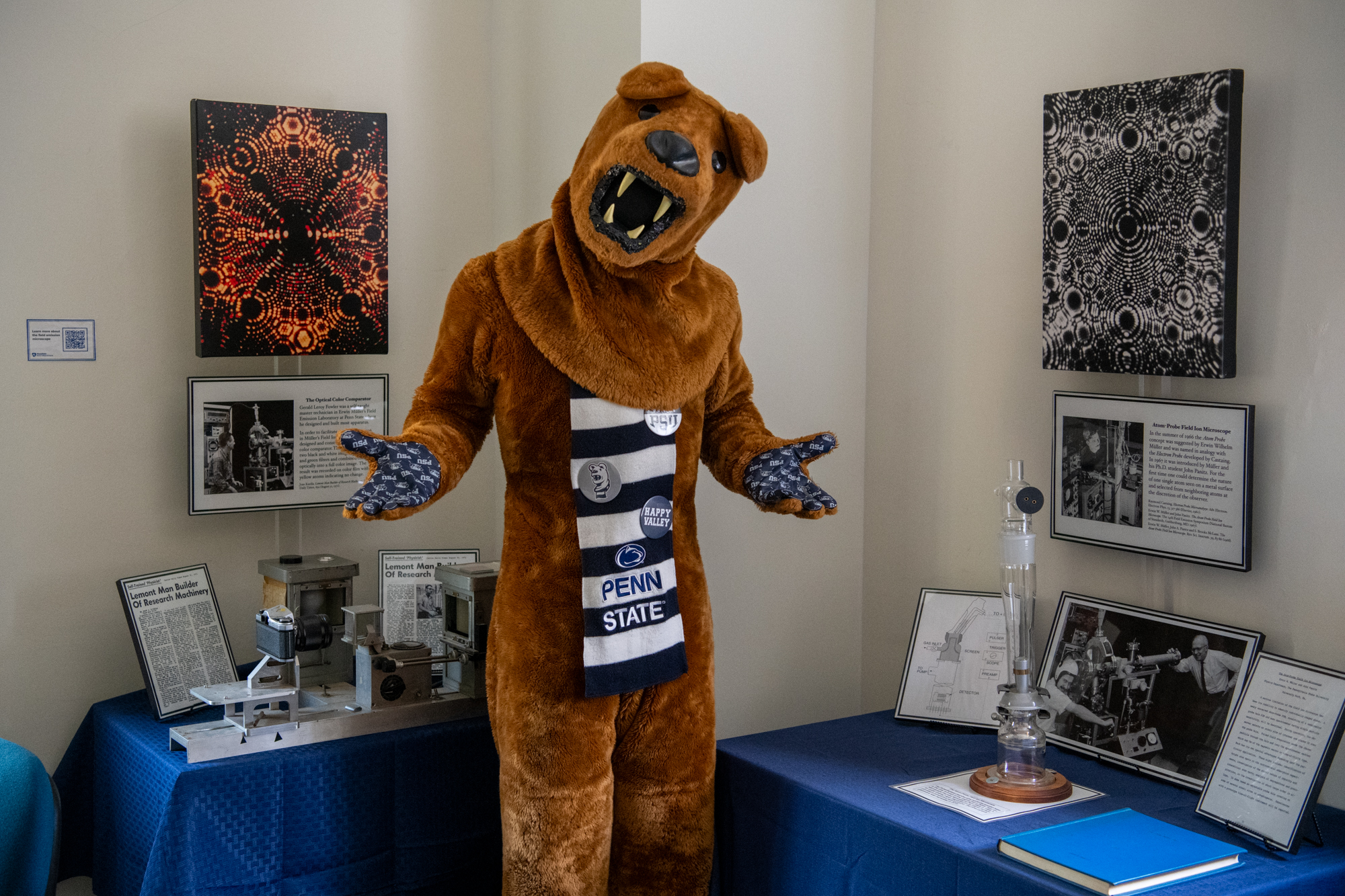The Nittany Lion poses with hands out in front of two pieces of the Müller Exhibition equipment.