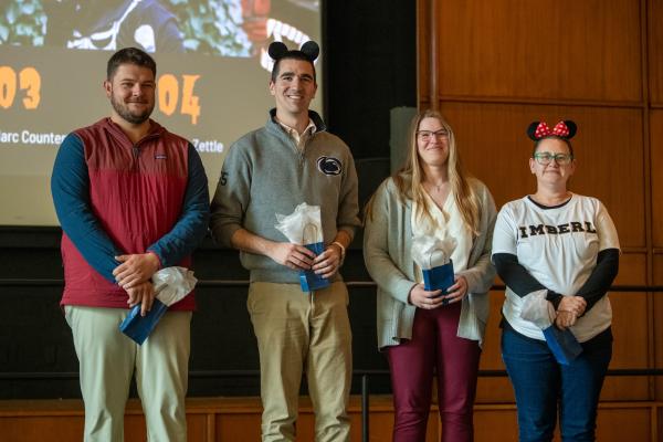 Group of four staff members on a stage.