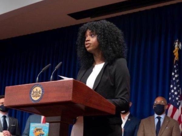 Ellis speaks at podium with american flag behind her