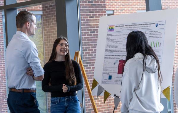 students present research poster to faculty member