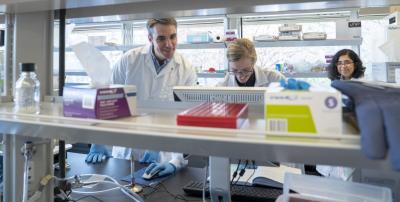 Kennedy and postdocs at lab bench