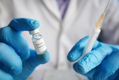 gloved hands holding vaccine vile and needle. Credit unsplash