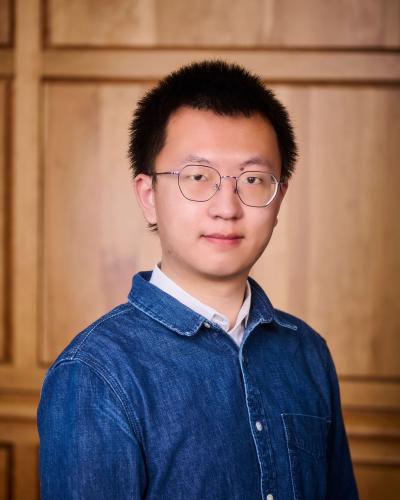 Yancheng Wang in front of wood paneling