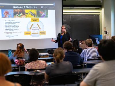Bordenstein presents in front of screen with students looking on