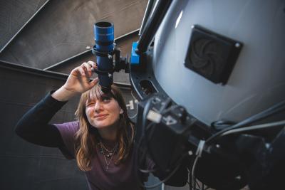A graduate student from the Department of Astronomy and Astrophysics working with a telescope.