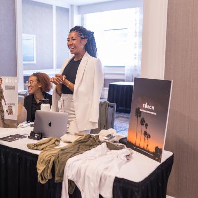Haley McClain Hill standing behind a table with products from her brand, TORCH Warriorwear.