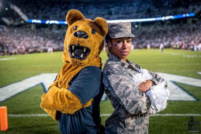 Haley McClain Hill in her Air Force uniform posing back to back with the Penn State Nittany Lion mascot