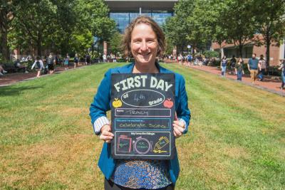 Dean Tracy Langkilde holding up a first day of school board.