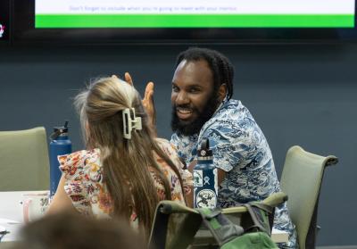 Two college members talk while seated at a table during an Evidenced-Based Teaching Academy event organized by The Grove Center.