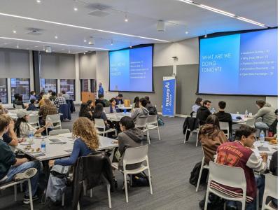 Group of students sitting at different tables during the Nittany AI Alliance.