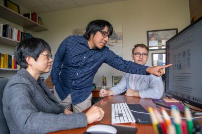 Jia Li sits in front of computer while a student points at screen
