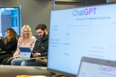 computer with ChatGPT slide in foreground with Morgan Vincent and students in back