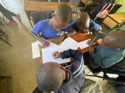 school students in Tanzania fill out worksheets