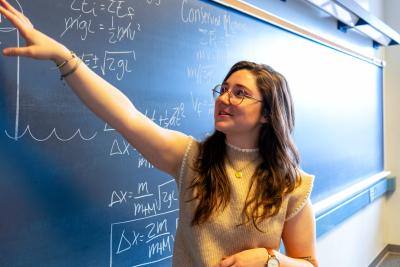 Emma Steinbronn teaching against a chalkboard.