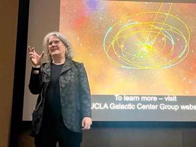 Andrea Ghez stands in front of projected screen