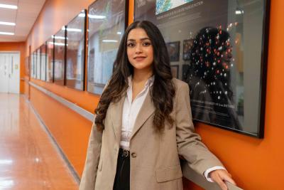 Person standing in a hallway with orange walls, framed scientific displays, and a polished floor.