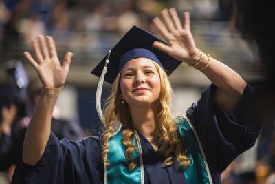 A brand new college aluma waves to her family at the Eberly College of Science commencement ceremony.