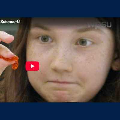 Girl participating in the Spherification Science-U at home experiment. This image is a close up of a girl popping one of the boba balls. 