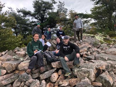 students sit on rocks and write in notebooks