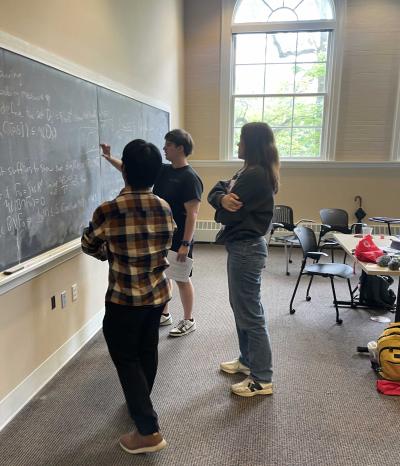 three math students work on a chalkboard