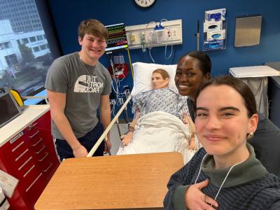 student take a selfie with a mannequin laying in a hospital bed