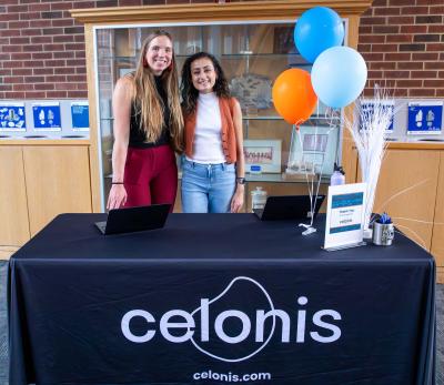 Kristina Kaldon and friend stand at table with Celonis tablecloth