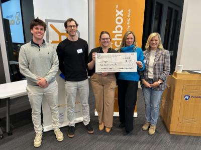 Maya Anderson, Eberly College of Science alumna, holding a check and posing for a photo with four other people.