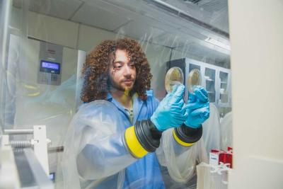 Shane Connolly wearing gloves and lab coat with hands in a fume hood