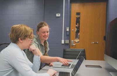 Charlotte Ward points at computer screen while grad student looks on