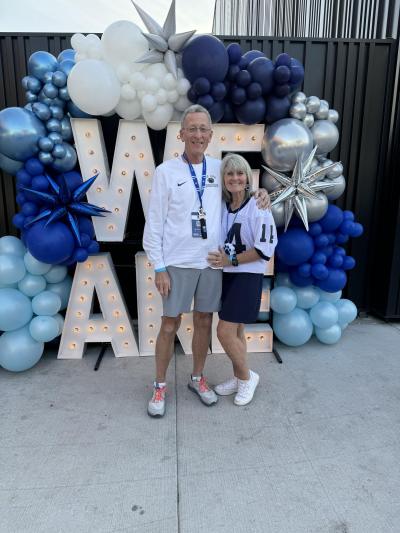 Jay and Kim Weitzel wearing Penn State clothes in front of We Are display with balloons