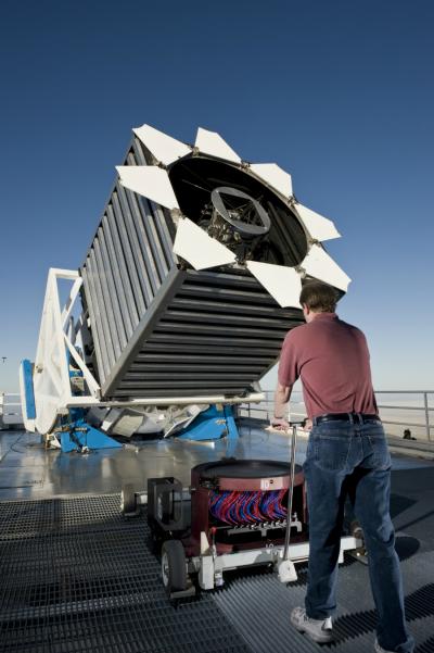 Credit: Dan Long, Apache Point Observatory Photograph of Senior Operations Engineer Dan Long loading the first Baryon Oscillation Spectroscopic Survey instrument cartridge of the night into the Sloan Digital Sky Survey telescope. The cartridge holds a "plug-plate" at the top, which positions a thousand optical fibers (red and blue). These cartridges are locked into the base of the telescope and are changed many times during a night.