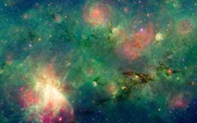  A dark, wispy cloud of dust seems to billow out from a bright explosion in this false-color image in infrared light from the Spitzer Space Telescope. These views have revealed that the mystery cloud, called M17 SWex, is forming stars at a furious rate but has not yet spawned the most massive stars -- O stars. To the left, on the trailing end of the dark cloud, such mammoth O stars create a dramatic contrast of brilliant light near the image's center.  Credit: NASA/JPL-Caltech/M. Povich (Penn State)