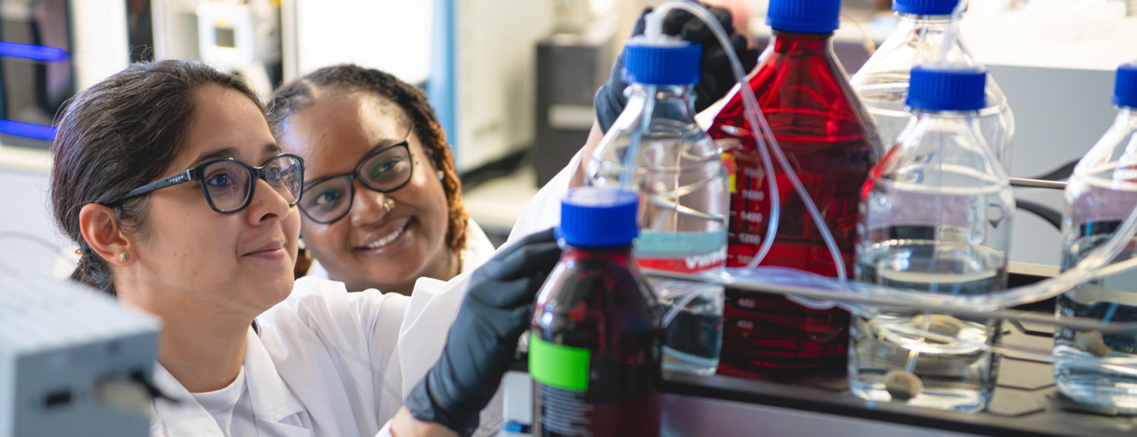 Two researchers look at vials in the laboratory of Melanie McReynolds, in the Department of Biochemistry and Molecular Biology