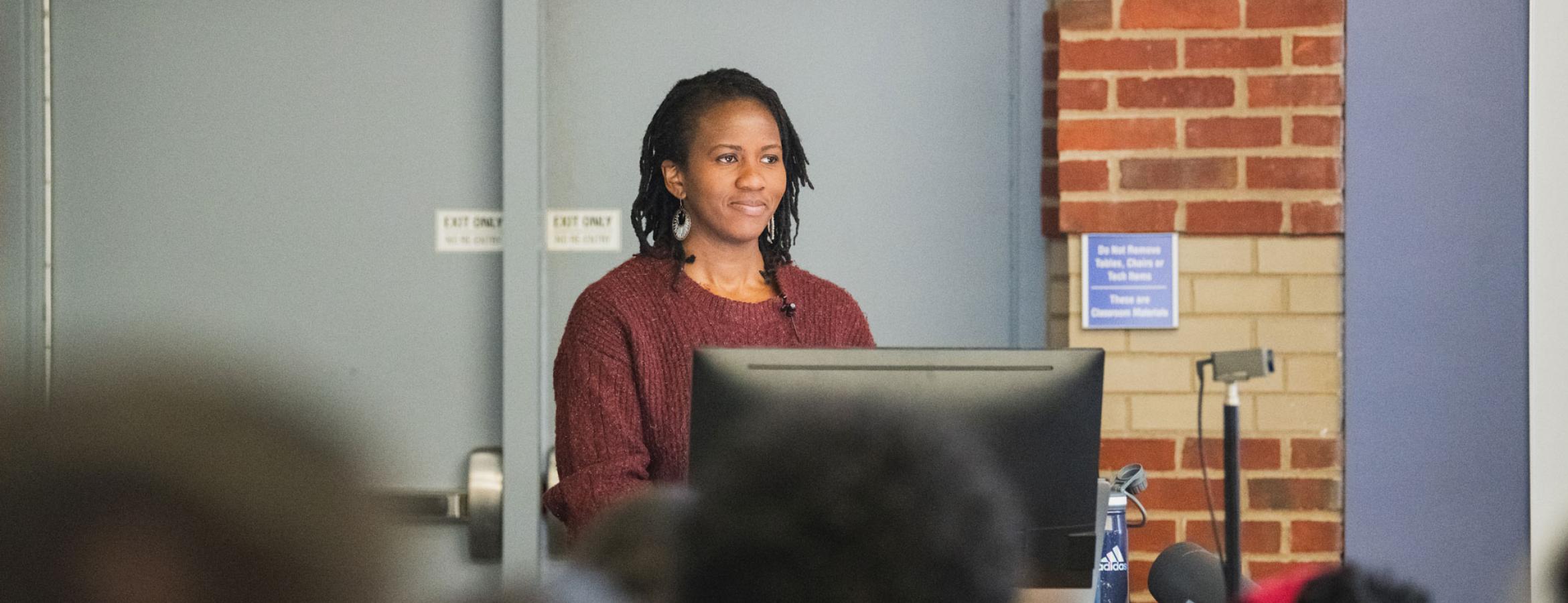 Denise Okafor stands at podium in classroom