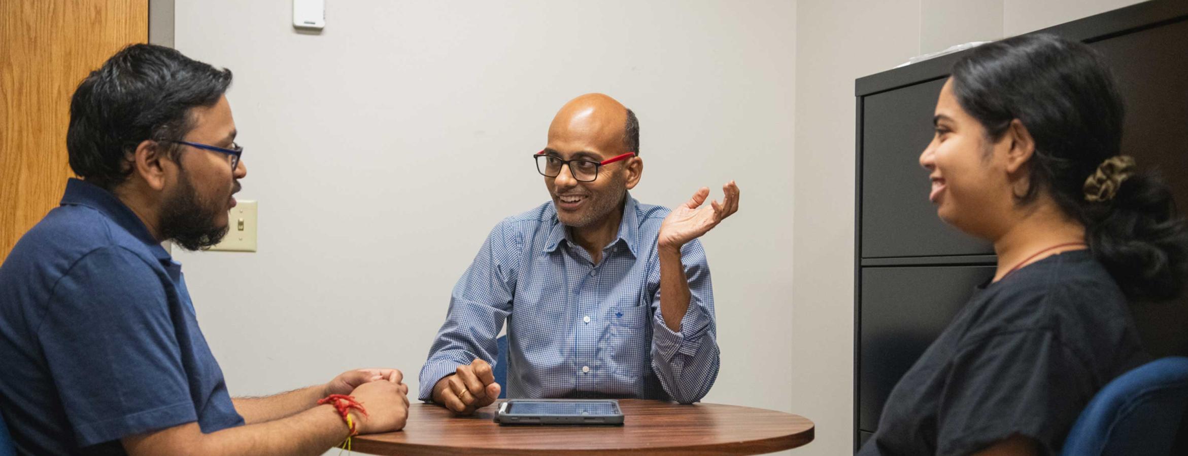 Bharath Sriperumbudur sits at table with two students