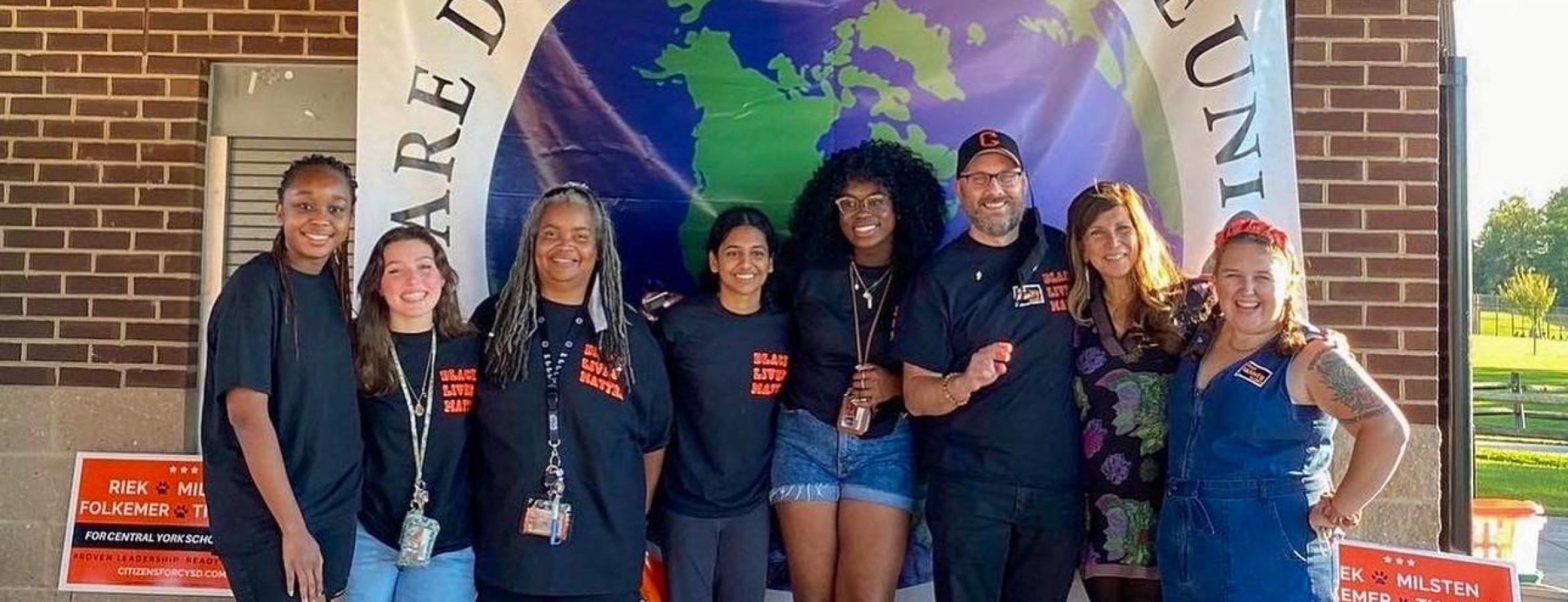 Ellis and other students pose under banner during book drive