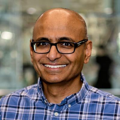 Portrait of a man with black-rimmed glasses and blue plaid shirt.
