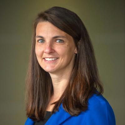 Picture of Katrina Merritt smiling in a blue blazer with a greenish gray background
