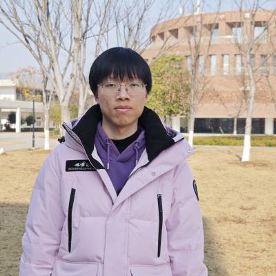 Bojun Zhang standing on grassland in front of a library.
