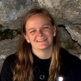 Portrait of Sydney Andrew smiling in front of a rock face
