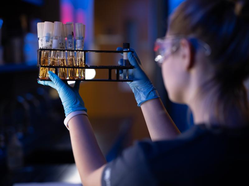 A student working in the lab holding up a case of viles as she check the labels on each vile.