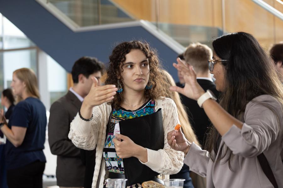 Two coeds waiting in line and talking during the Eberly College of Science fall 2024 networking reception.