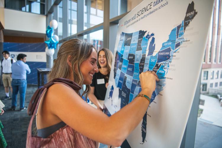 An undergraduate student marks the map where she will go to medical school during the premedicine celebration event.