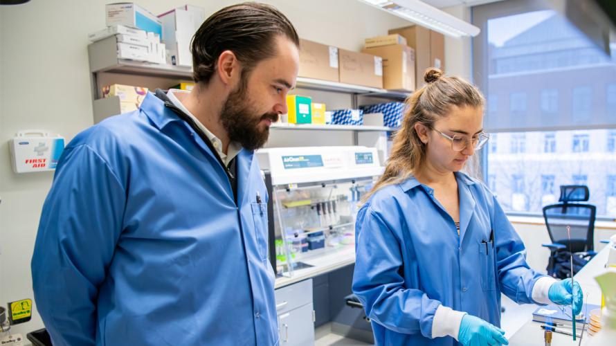 Jordan Bisanz working with a graduate student in his lab.