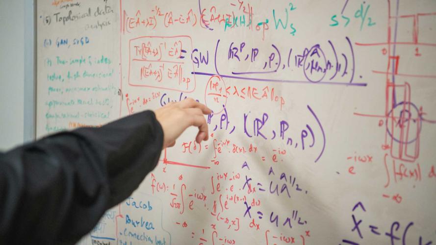 hand points to whiteboard with stats and math equations