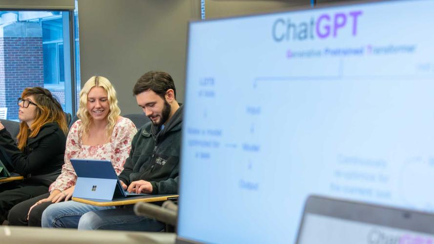 computer with ChatGPT slide in foreground with Morgan Vincent and students in back
